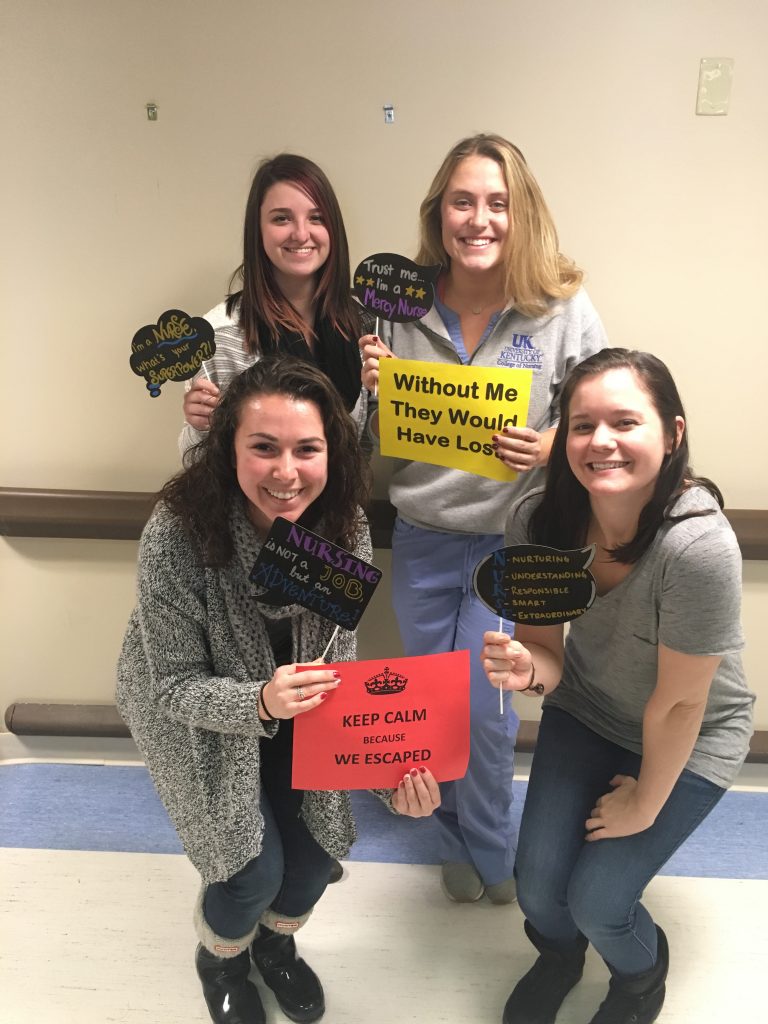four Escape Room participants holding signs indicating they escaped and won the game