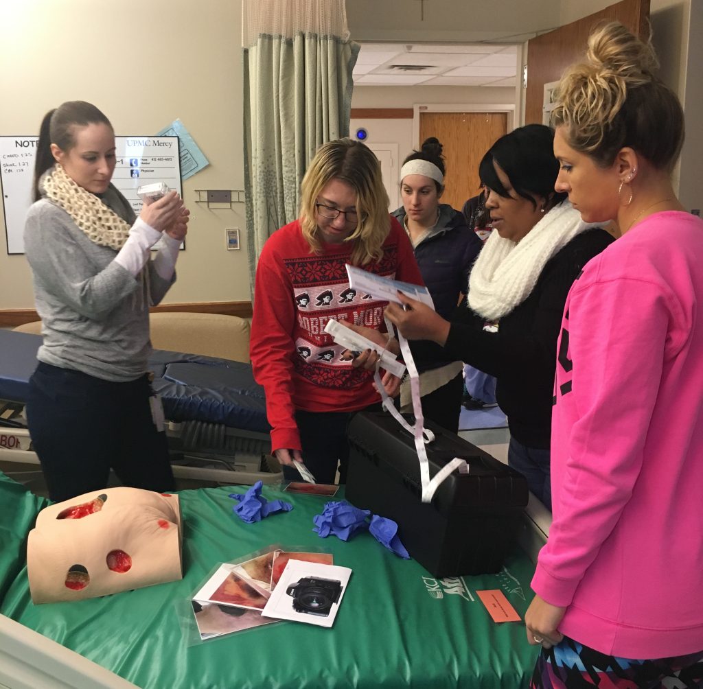 escape room participants standing over a hospital bed with clues gathered together