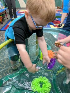 Child interacting with toys in a tub full of water