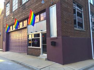 The corner of Bradbury-Sullivan LGBT Community Center’s building, featuring three rainbow flags on the left wall.