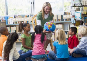 Librarian and children looking at globe in library