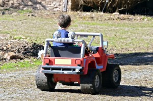 A young boy having fun driving his toy car outdoors.