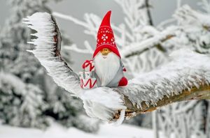 Little figurine of Santa standing in snow, holding gifts