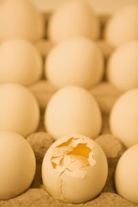 Broken egg in a carton with other eggs, showing how the attention is drawn to negatives.