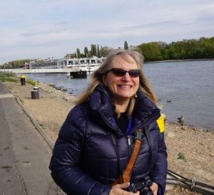 Susan Wolfe standing beside a river in Europe