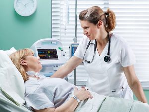 Hosptial patient with surgical nurse at the bedside.