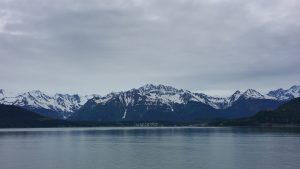 snow topped mountains with gray sky and water