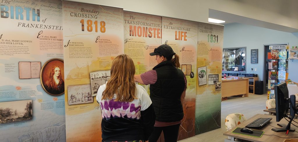Two women reading information on an NNLM traveling exhibit