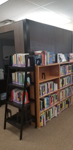 Multiple bookshelves outside of a privacy pod with whiteboard.