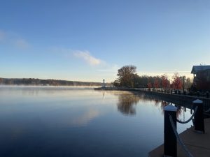 Calm lake with trees in the background and a wooden dock in the foreground