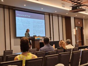Woman standing at a podium presenting.