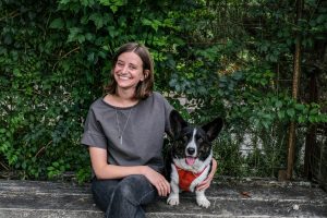 Photo of Emily Hamstra sitting on a bench with a and a black and white dog