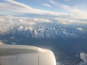 view from airplane window showing snow covered mountains