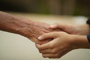 A young person holding the hand of an older person