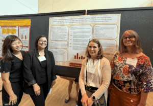 members of Keck Medicine of USC’s Nursing Research and Evidence-Based Practice Council standing in front of their poster at a symposium