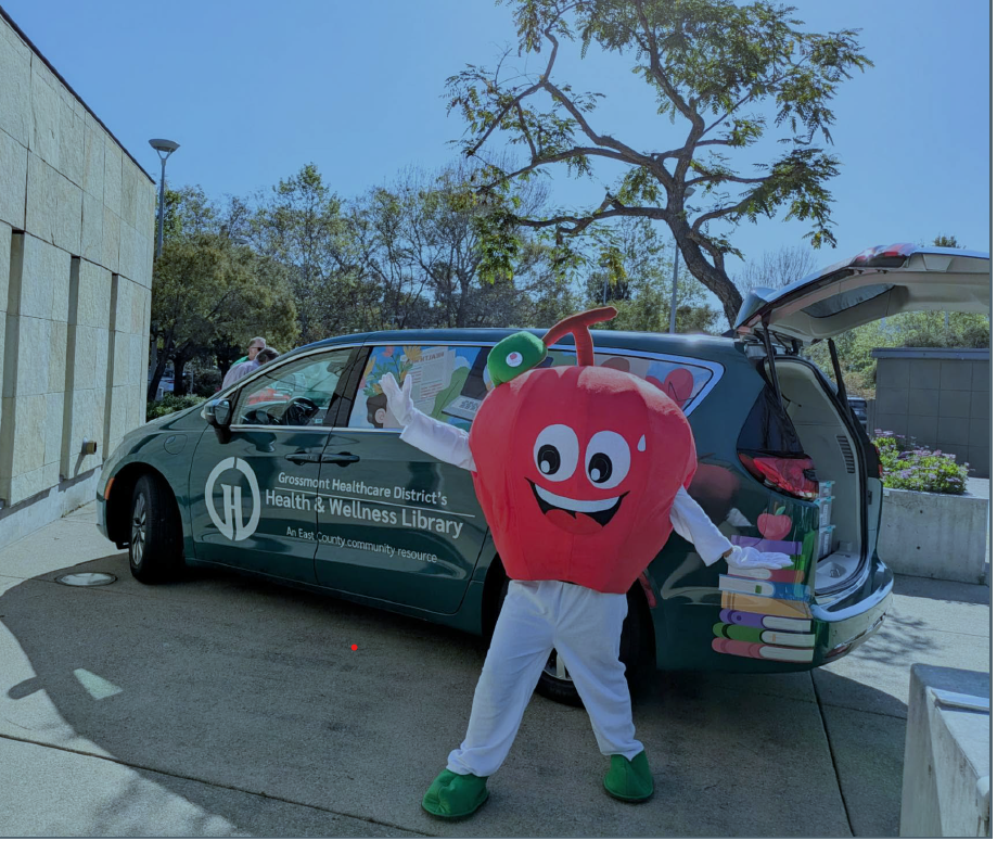 apple mascot standing in front of the Grossmont mobile library van