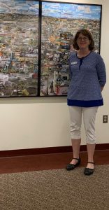 Jane Fisher, Director of Wallingford Public Library, beside a photo collage of the town of Wallingford