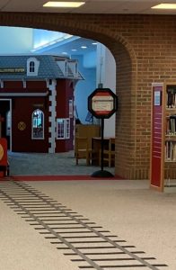 Wallingford Public Library Children's area with carpet patterned to look like train tracks leading to a playhouse replica of the Wallingford Train Station