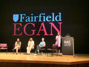 Photo of Panel Discussion at Fairfield University including three students who are seated and the moderator, Tanika Eaves, who is standing. 